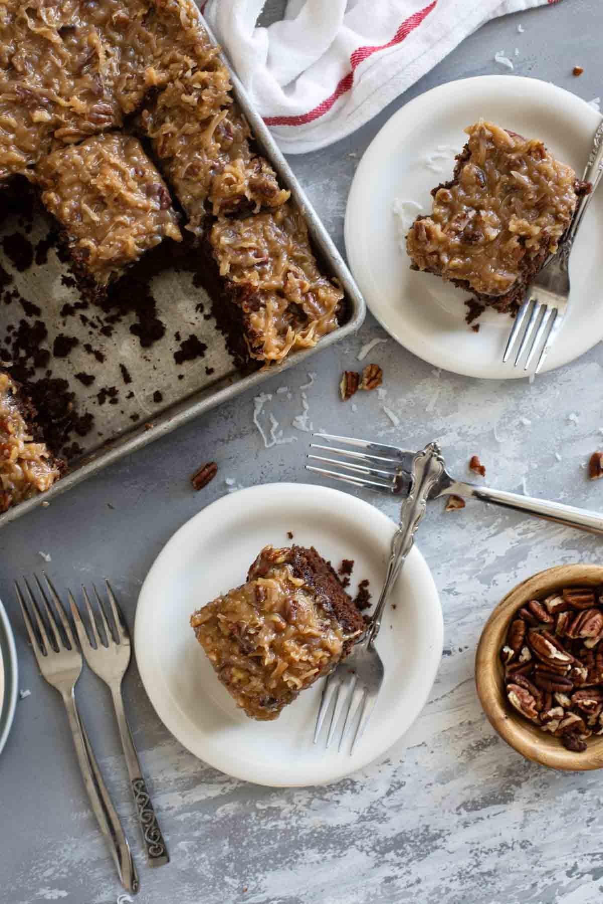 Slices of German Chocolate Cake on plates with the baking pan of cake nearby.
