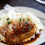 Glazed Pork Chops with mashed potatoes, with parsley sprinkled on top.