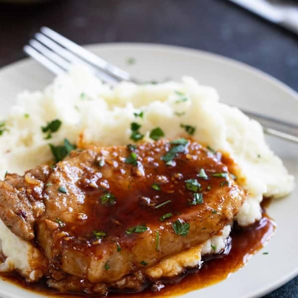 Glazed Pork Chops with mashed potatoes, with parsley sprinkled on top.