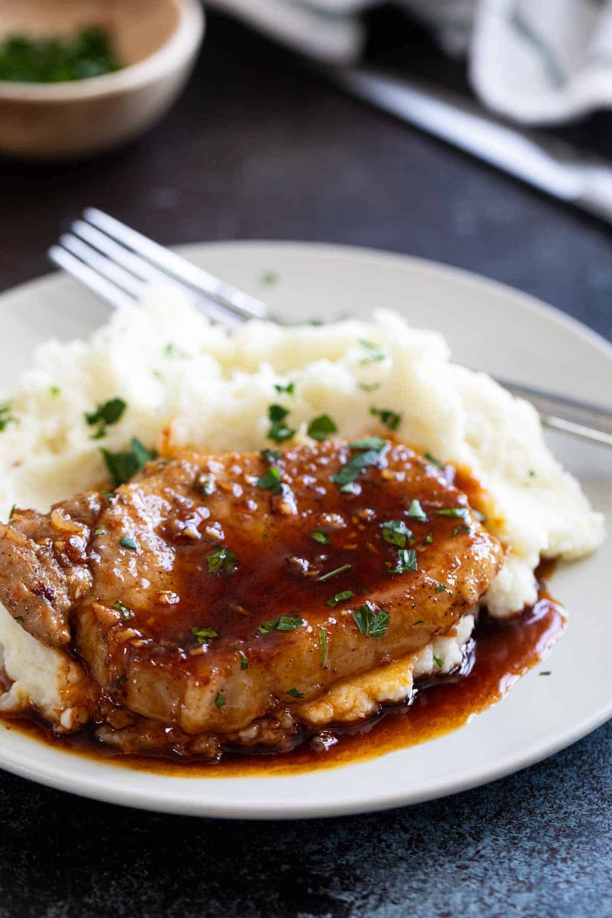Glazed Pork Chops with mashed potatoes, with parsley sprinkled on top.