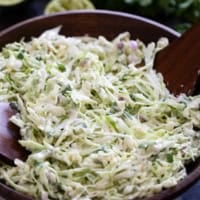 Cilantro Lime Slaw in a wooden bowl with wooden spoons.
