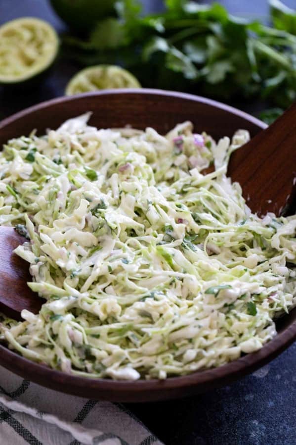 Cilantro Lime Slaw in a wooden bowl with wooden spoons.