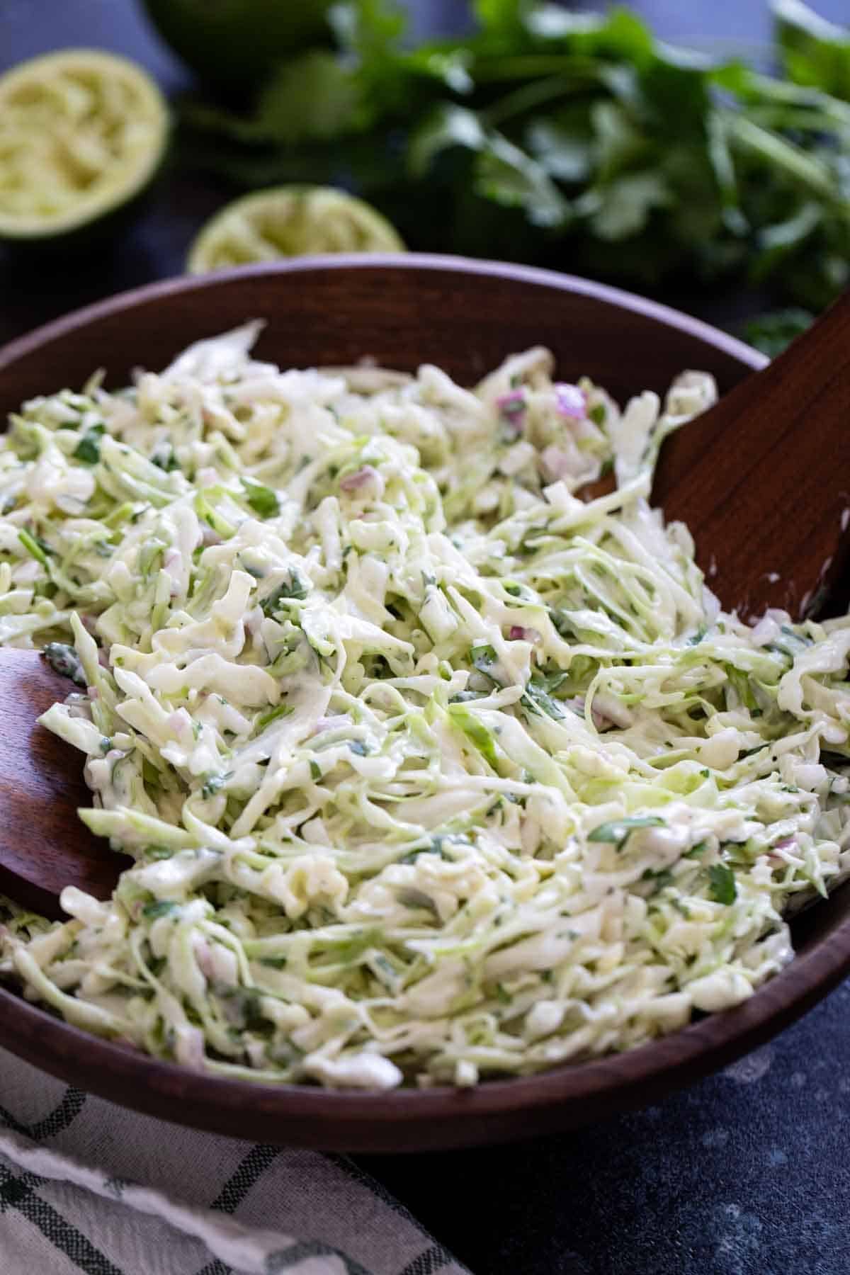 Cilantro Lime Slaw in a wooden bowl with wooden spoons.