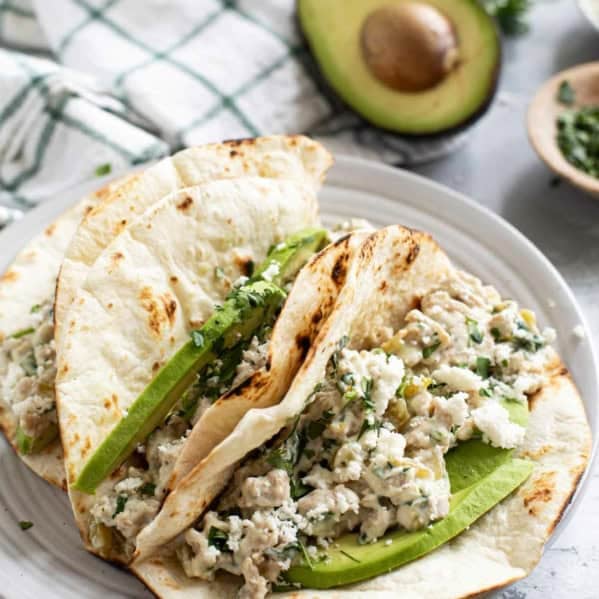 Creamy Chicken Tacos with avocado, and topped with cilantro and queso fresco.