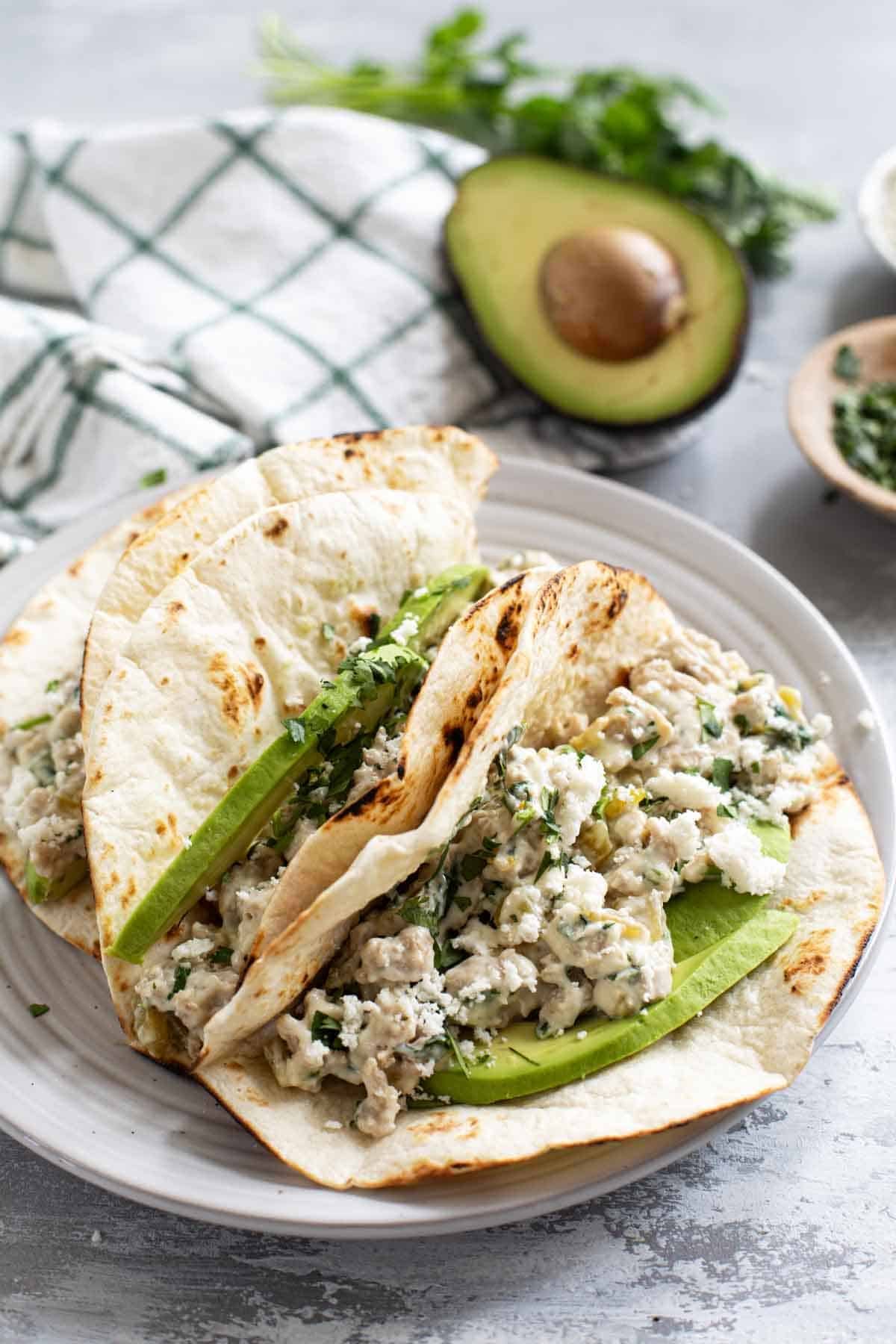 Creamy Chicken Tacos with avocado, and topped with cilantro and queso fresco.