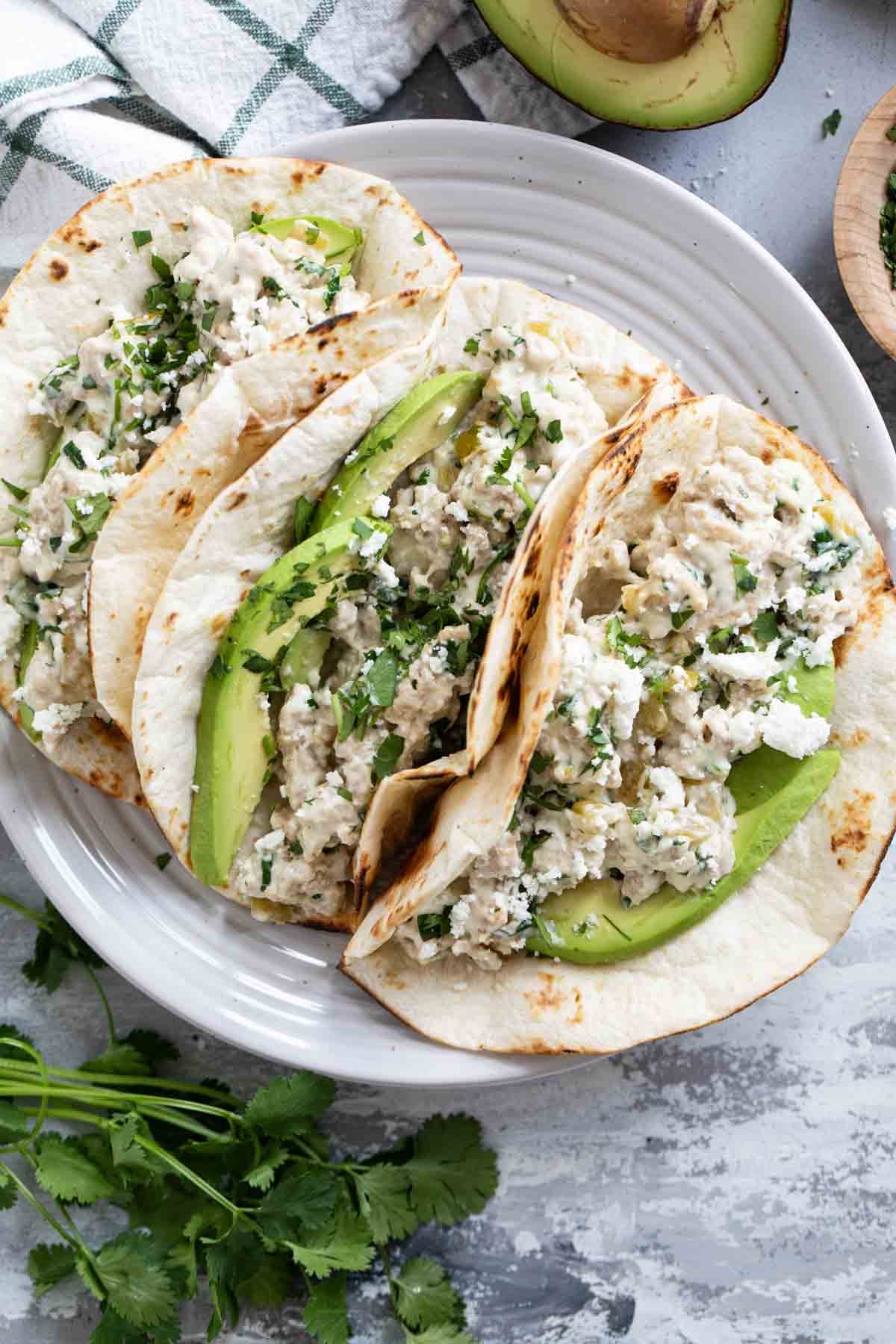 Three Creamy Chicken Tacos with avocado on a plate.