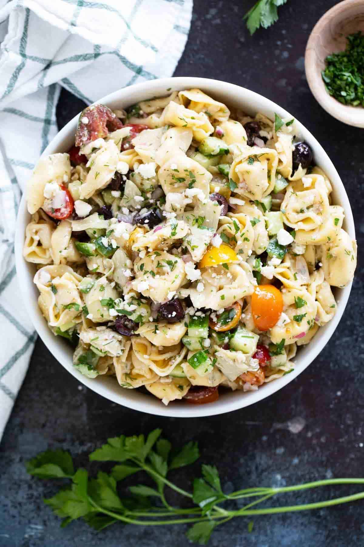 Bowl filled with Greek Tortellini Pasta Salad topped with feta.
