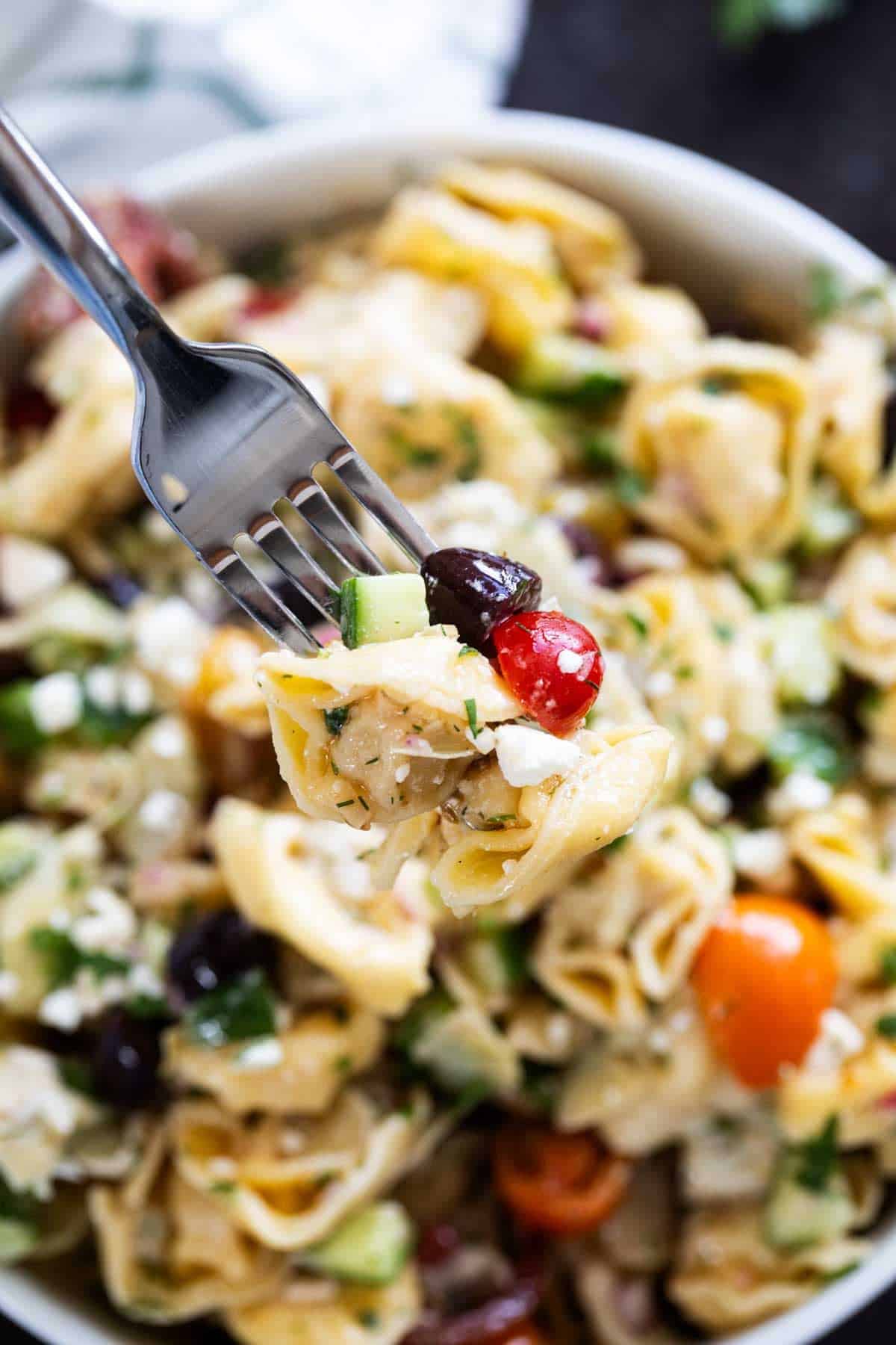 Fork with a bite of Greek Tortellini Pasta Salad.