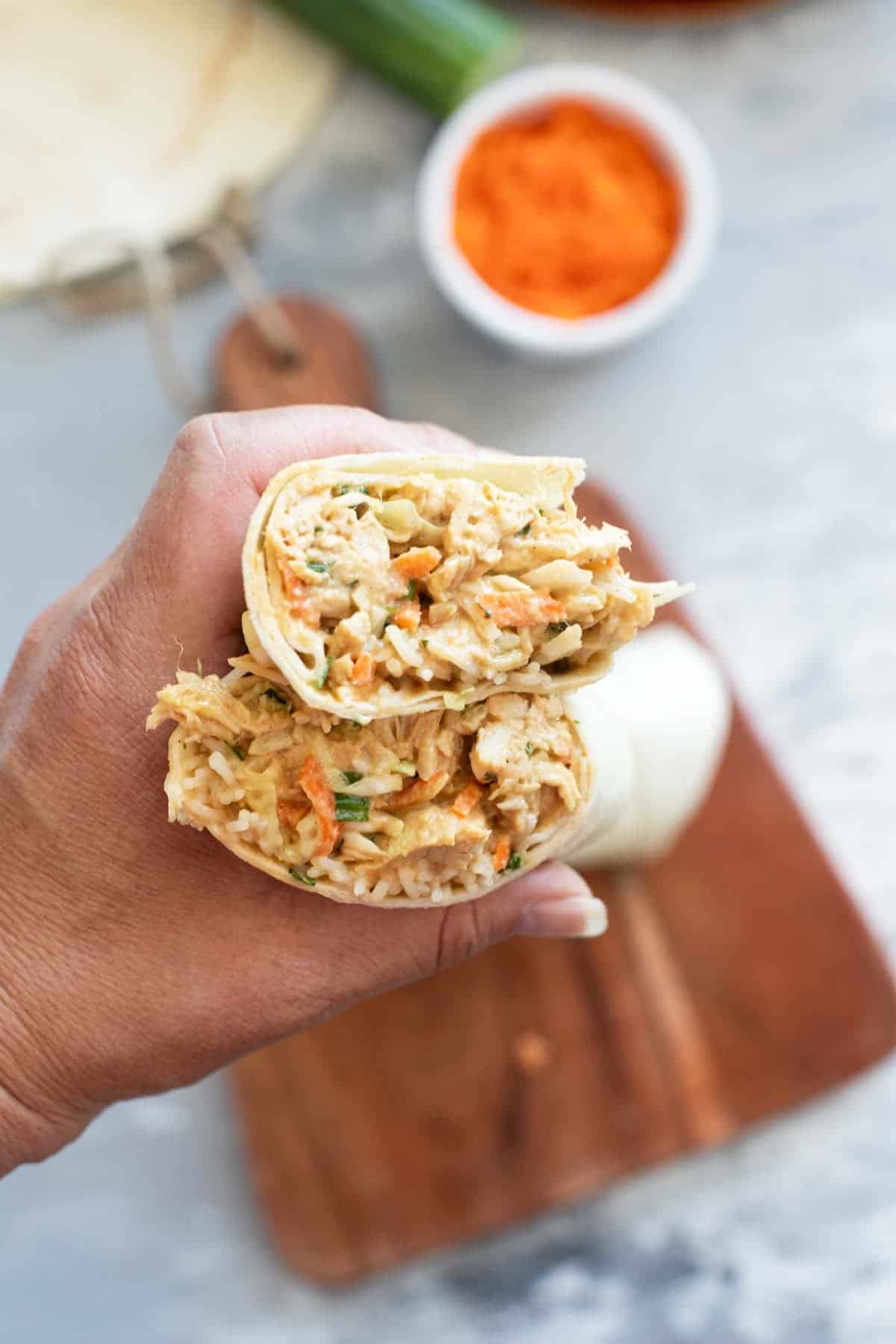 Holding a Thai Chicken Wrap that is cut in half.