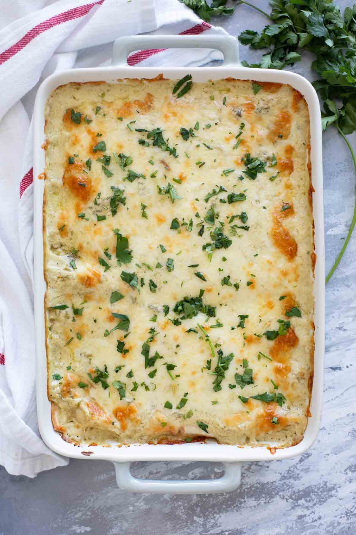 Casserole dish of White Chicken Enchiladas topped with cilantro.