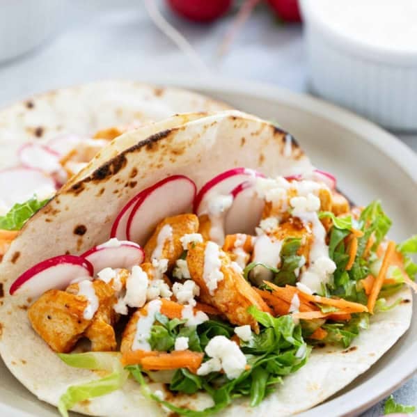 Buffalo Chicken Tacos on flour tortillas, topped with lettuce, carrots, radishes, and blue cheese dressing.