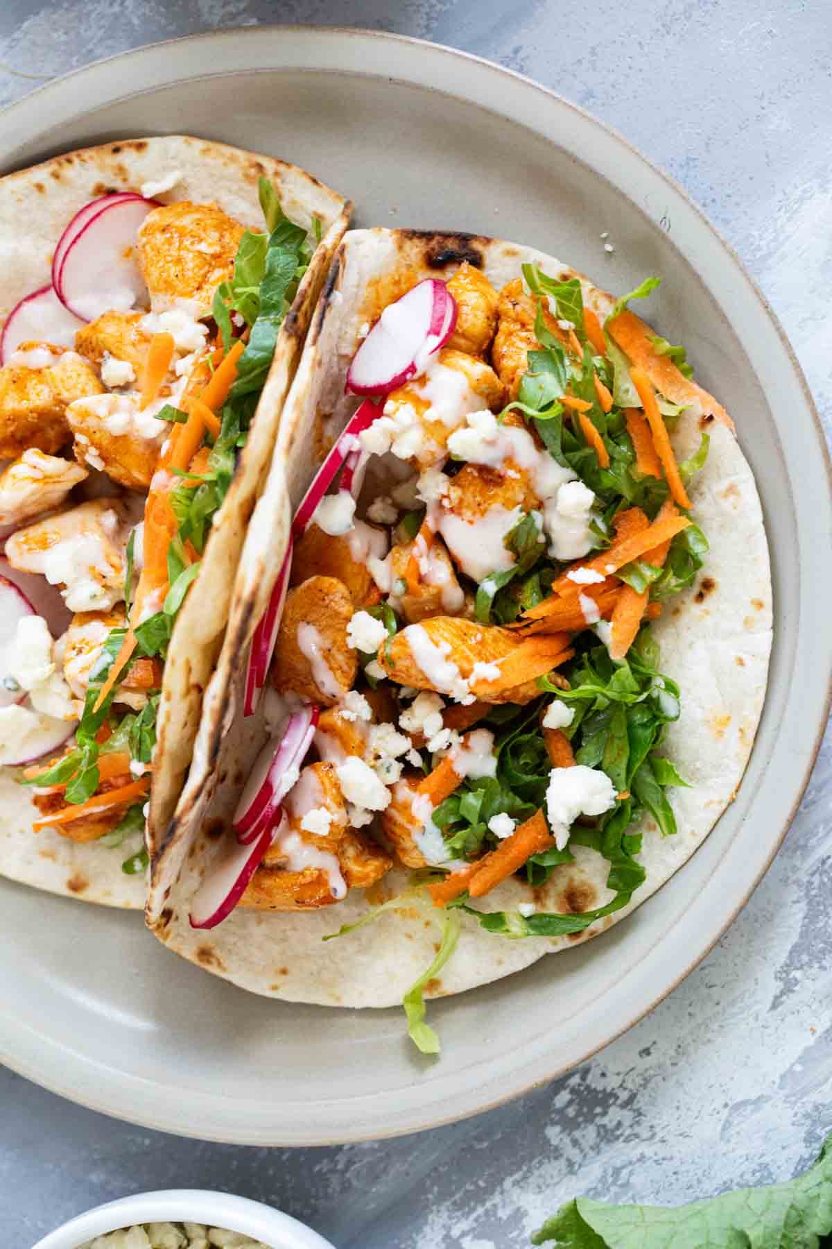 Two buffalo chicken tacos on a plate.