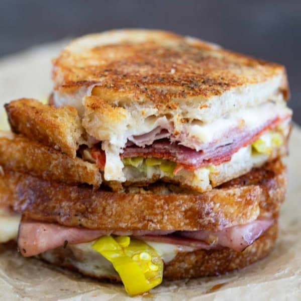 Italian Grilled Cheese sandwich cut in half and stacked, with a bite taken from one half.