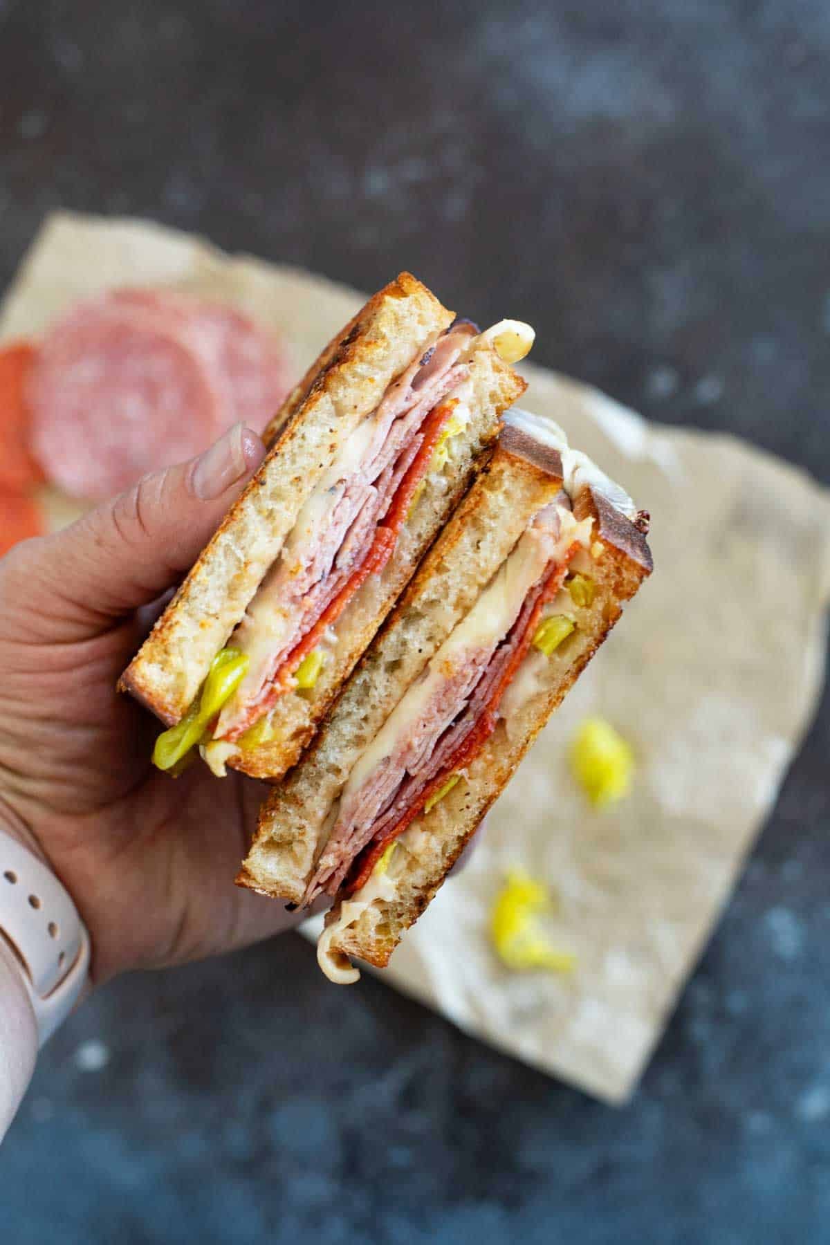 Hand holding an Italian grilled cheese sandwich that is cut in half.