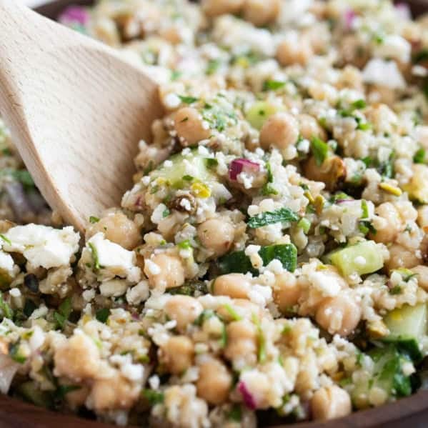 Jennifer Aniston Salad, topped with feta cheese, in a bowl with a wooden serving spoon.