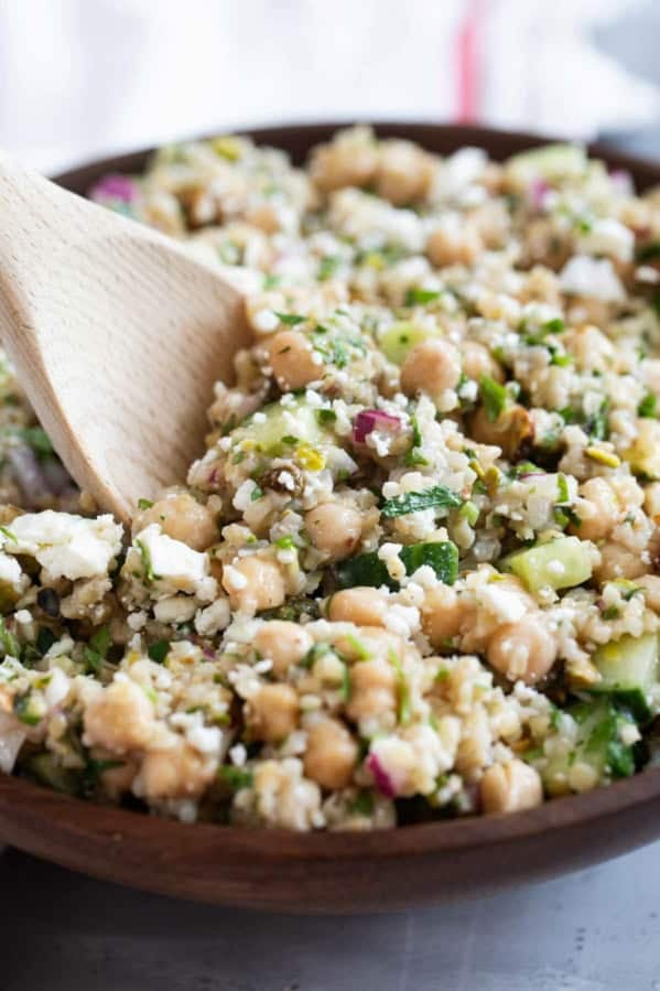 Jennifer Aniston Salad, topped with feta cheese, in a bowl with a wooden serving spoon.