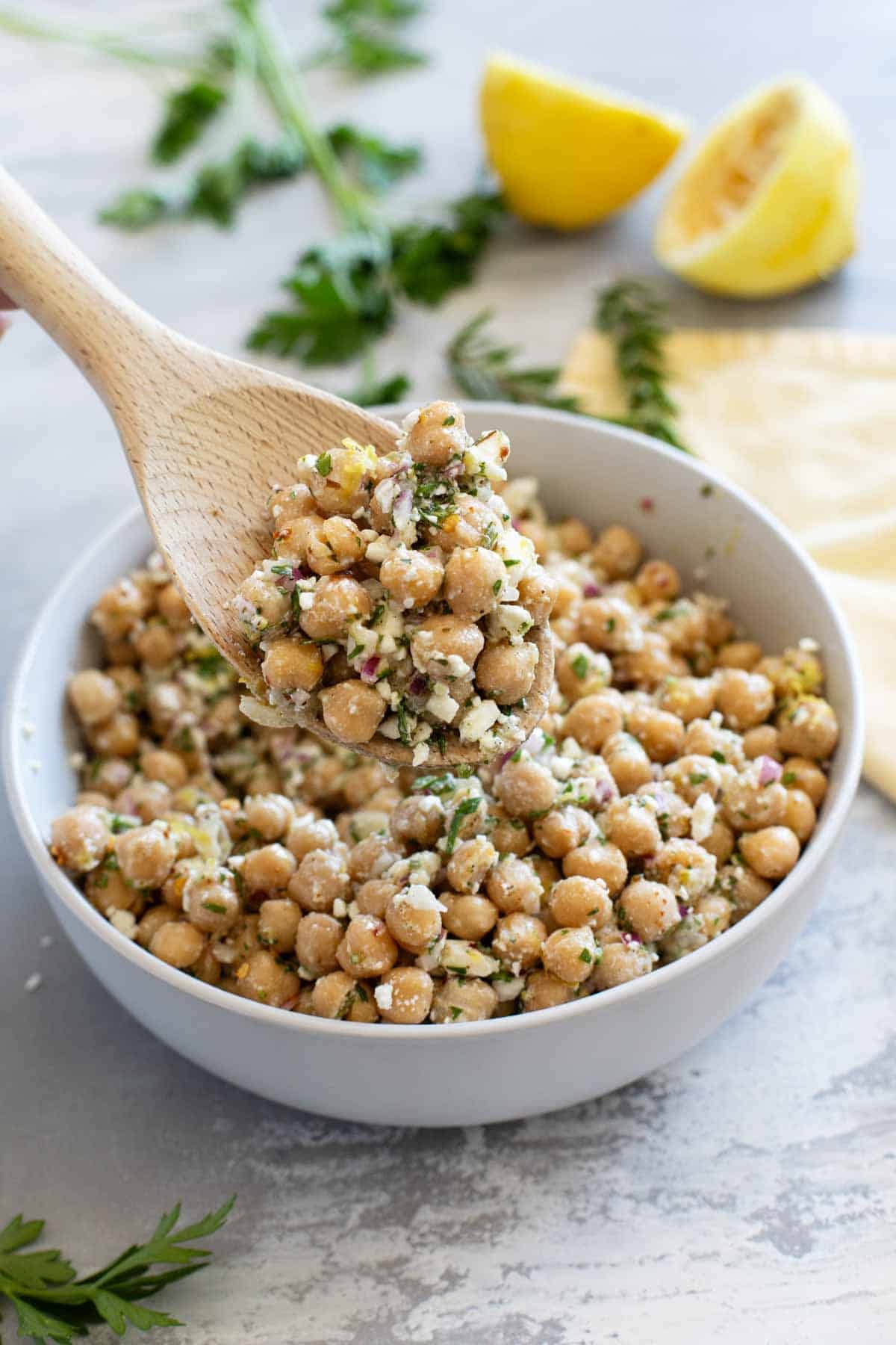 Bowl of Lemon Chickpea Salad with a wooden serving spoon.