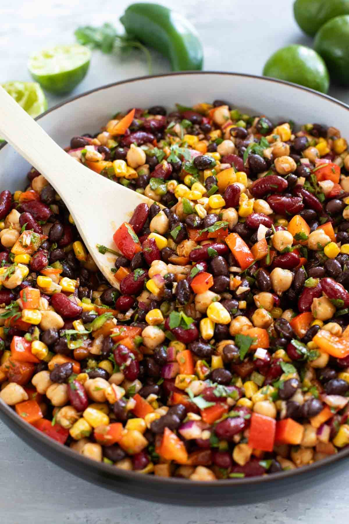 Bowl of Mexican Bean Salad with a wooden serving spoon.