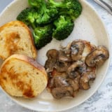 Pork Chop with Dijon Mushrooms on a plate with a fork and side dishes.