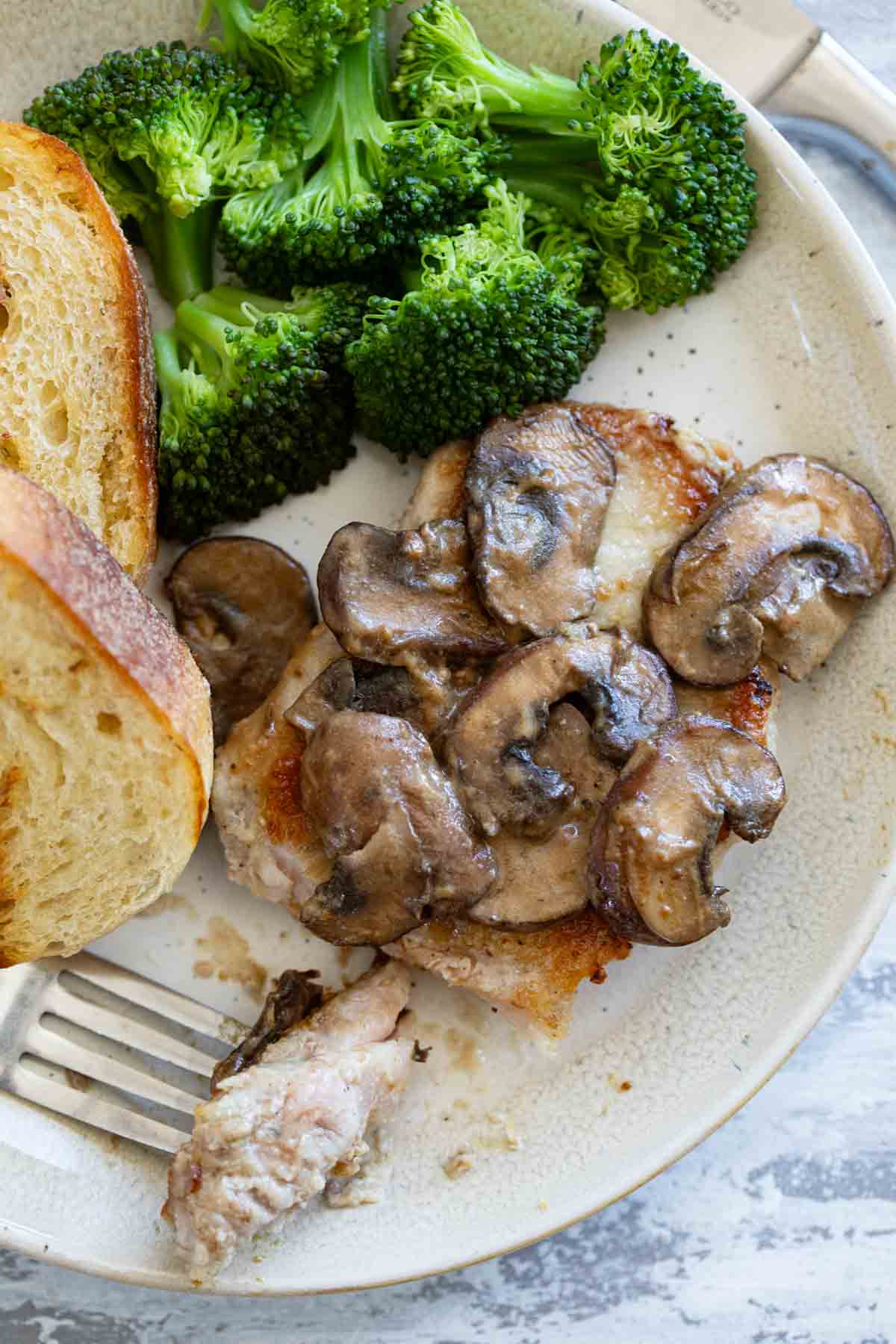 Pork Chop with Dijon Mushrooms on a plate with a bite taken from the pork chop.