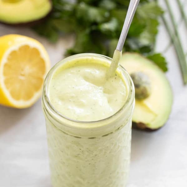 Jar filled with Avocado Ranch Dressing with a spoon in the jar.