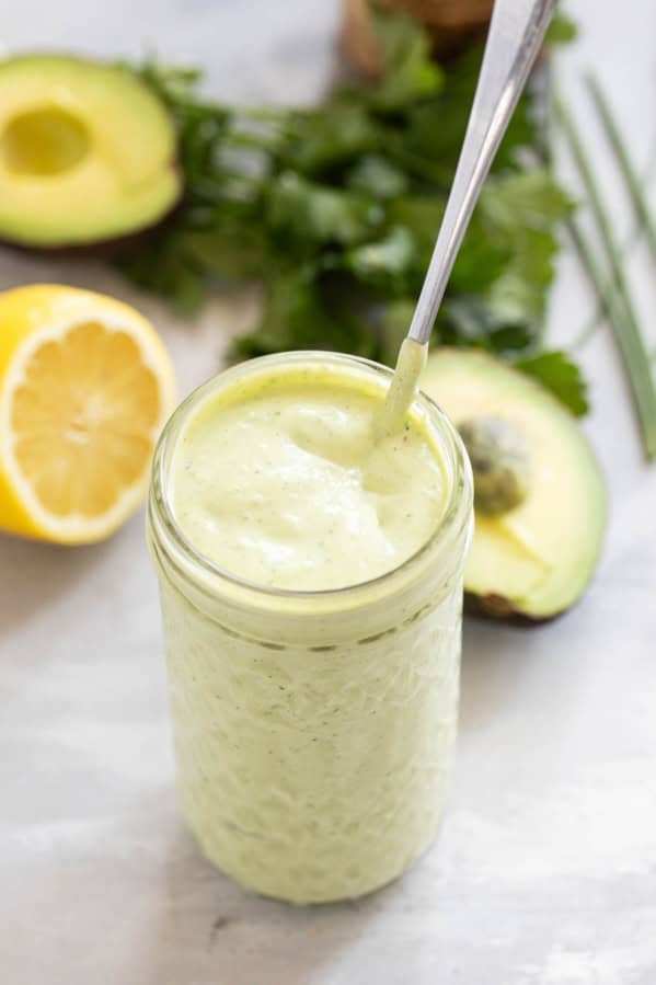 Jar filled with Avocado Ranch Dressing with a spoon in the jar.