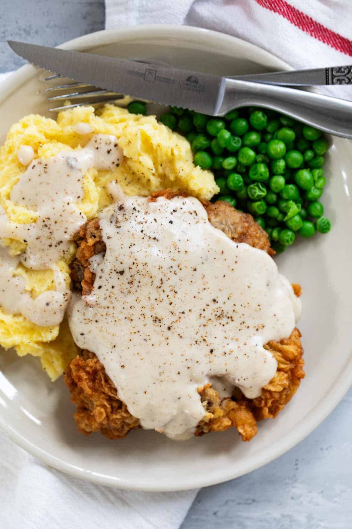 Chicken Fried Steak with country gravy, mashed potatoes, and peas.