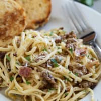 Sausage Carbonara Pasta with bacon on a plate served with toasted bread.