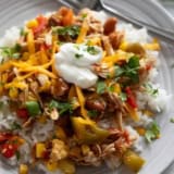 Slow Cooker Tex-Mex Chicken over rice, topped with cheese, sour cream, and cilantro.