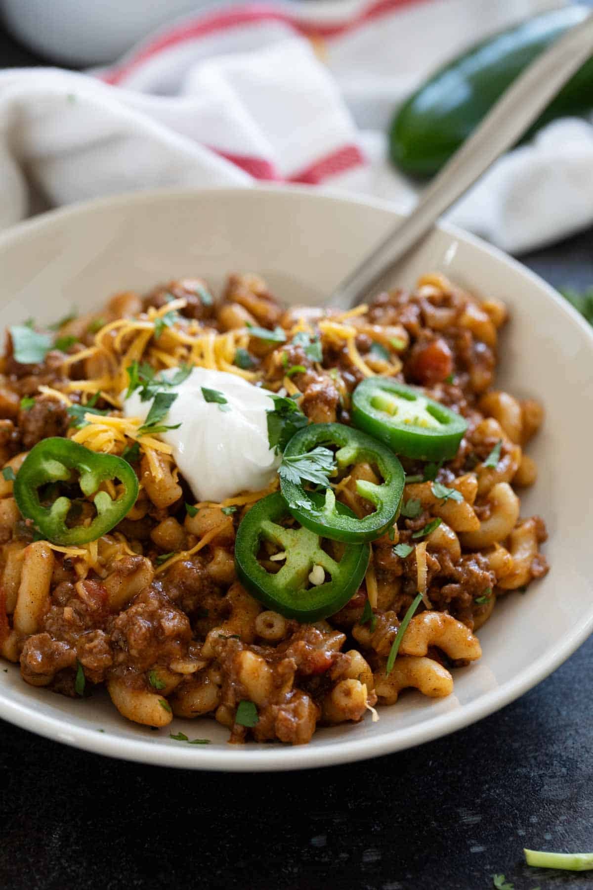 Bowl of Taco Pasta topped with sour cream, cheese, jalapeños, and cilantro.