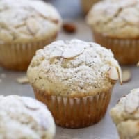 Almond Poppy Seed Muffins topped with sliced almonds and powdered sugar.