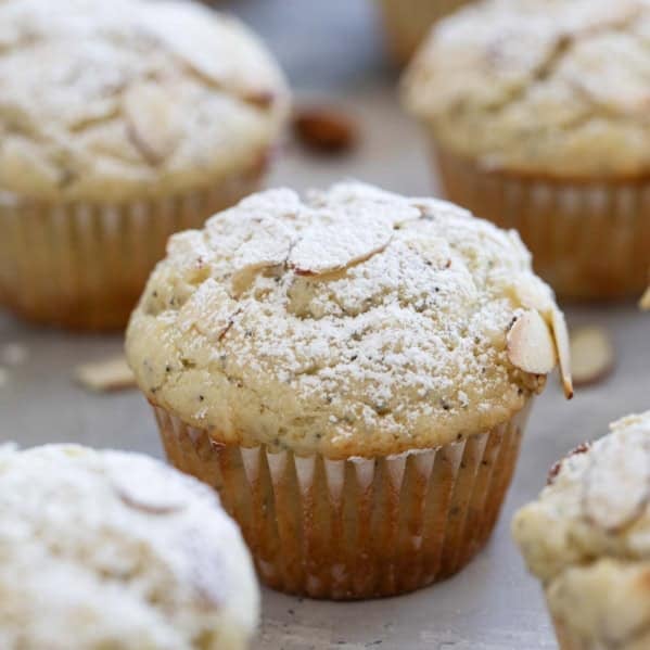 Almond Poppy Seed Muffins topped with sliced almonds and powdered sugar.