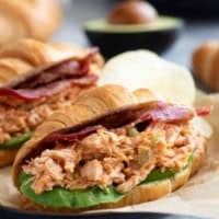 BBQ Ranch Chicken Salad Sandwiches on croissants with sliced avocado and bacon.