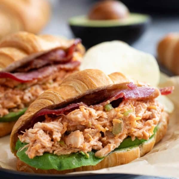 BBQ Ranch Chicken Salad Sandwiches on croissants with sliced avocado and bacon.