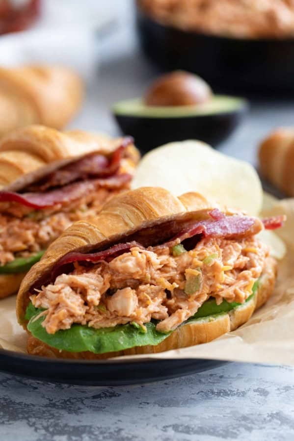 BBQ Ranch Chicken Salad Sandwiches on croissants with sliced avocado and bacon.