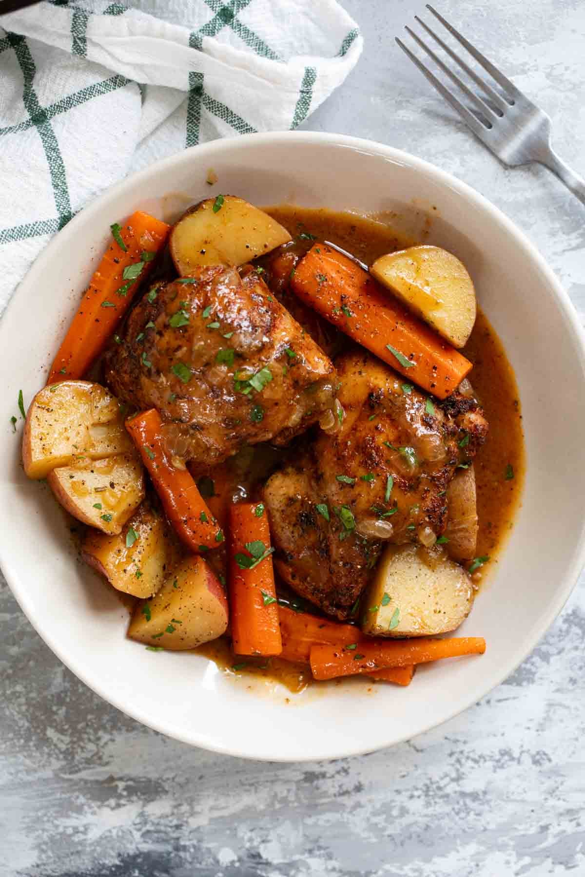 Serving of Braised Chicken Thighs with Carrots and Potatoes in a shallow bowl.