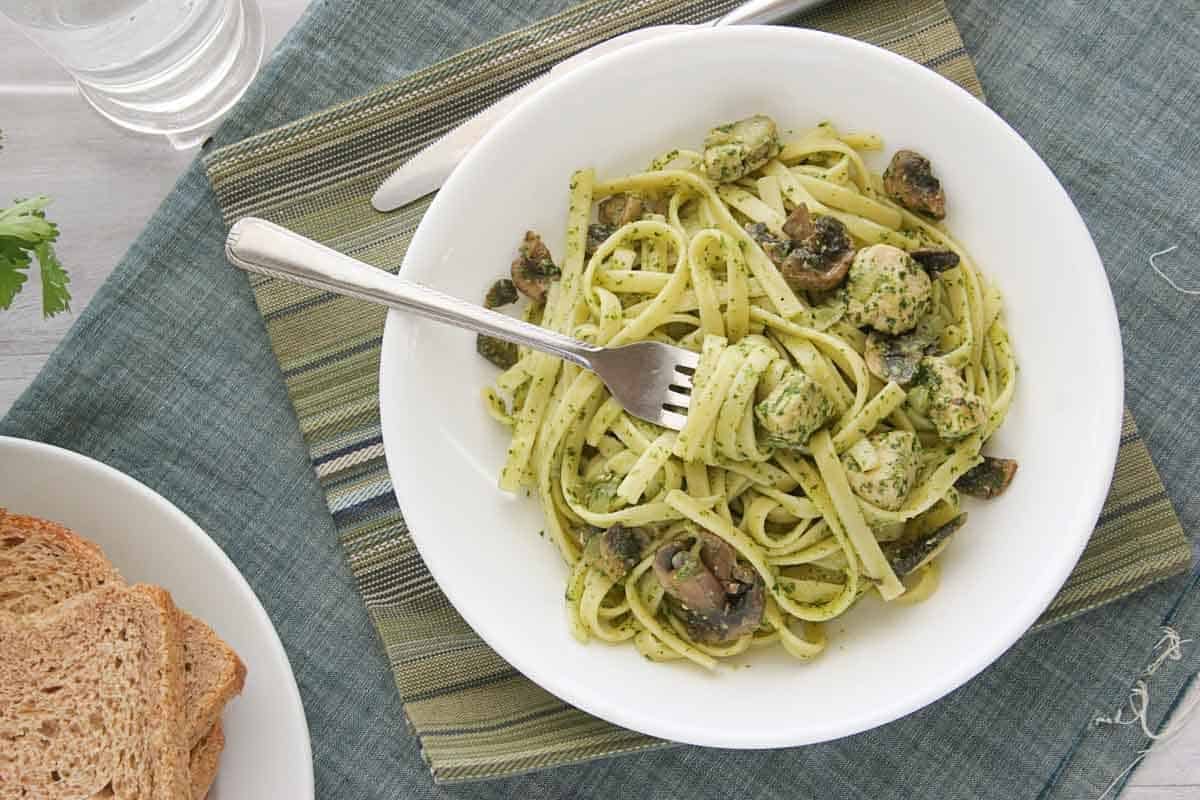 Bowl of Chicken and Pasta with Cilantro Pesto with a fork in the pasta.