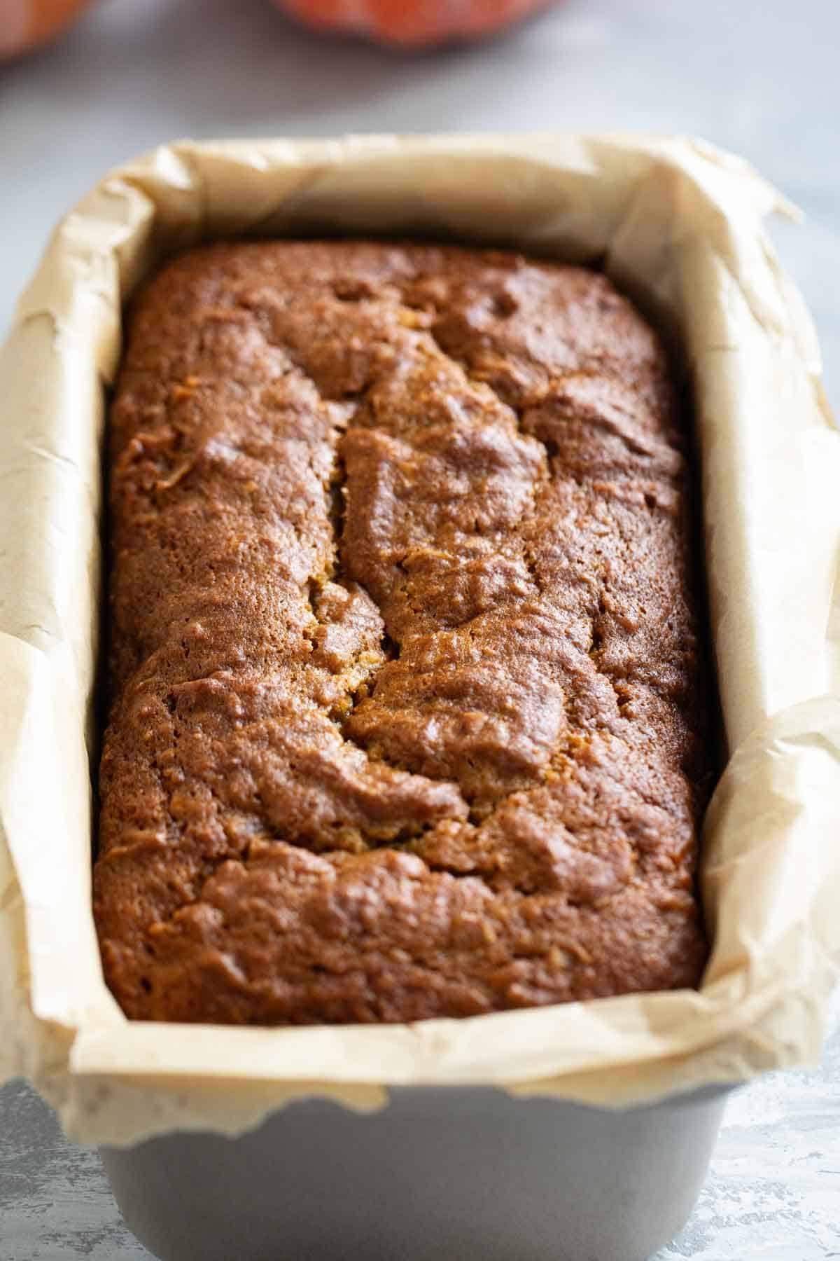 Loaf of Pumpkin Coconut Bread in a parchment paper lined loaf pan.