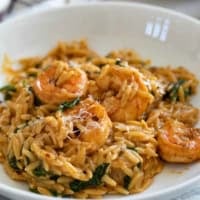 Serving of Shrimp Orzo Skillet on a plate, topped with fresh parmesan cheese.