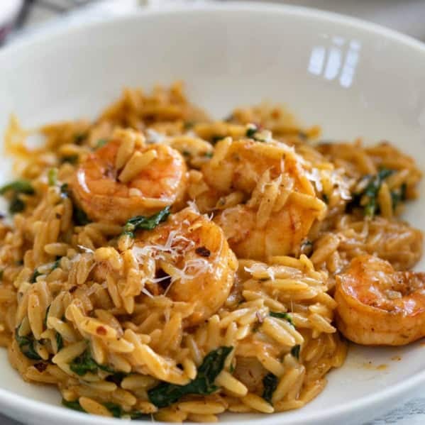 Serving of Shrimp Orzo Skillet on a plate, topped with fresh parmesan cheese.