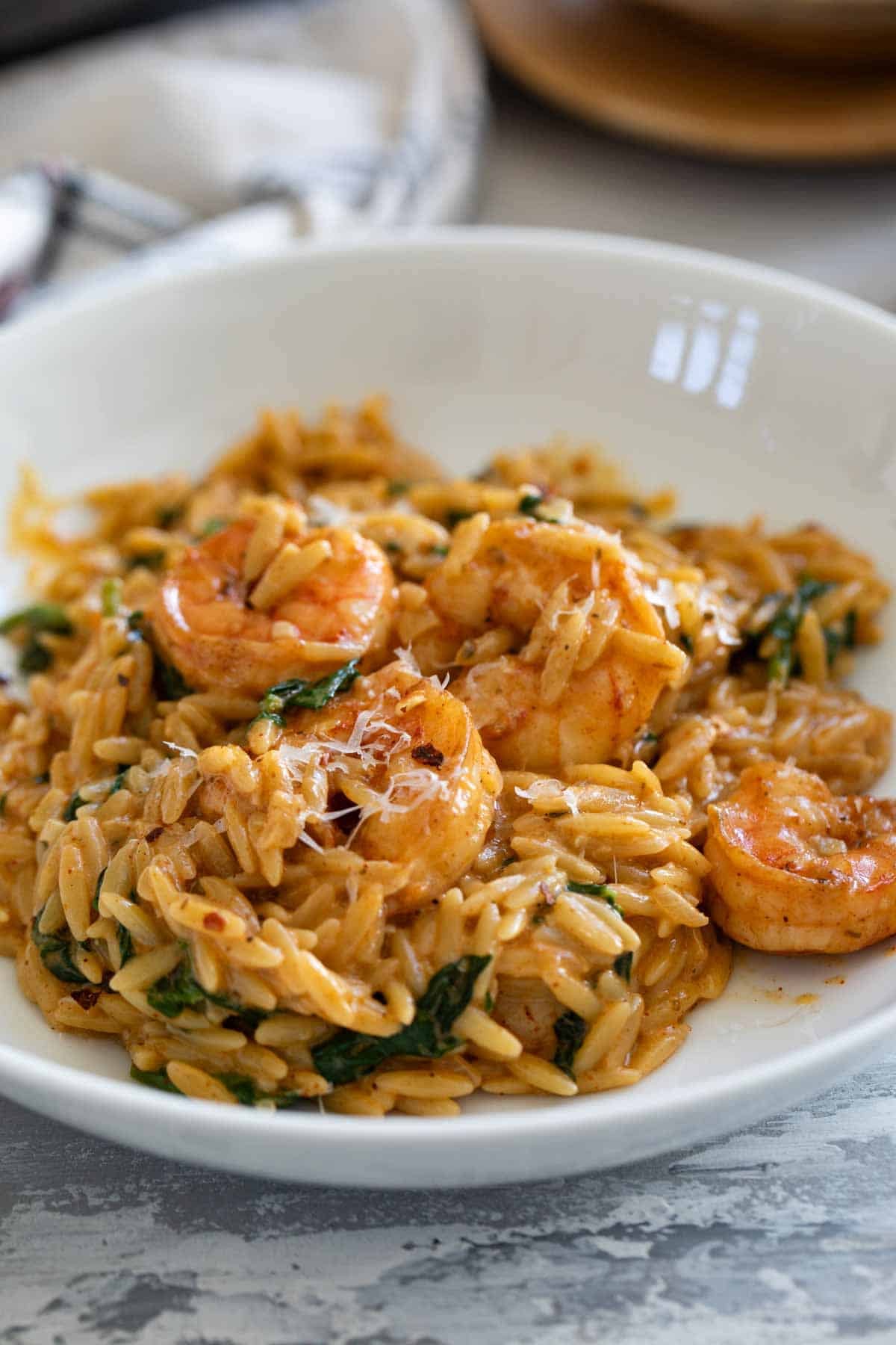 Serving of Shrimp Orzo Skillet on a plate, topped with fresh parmesan cheese.