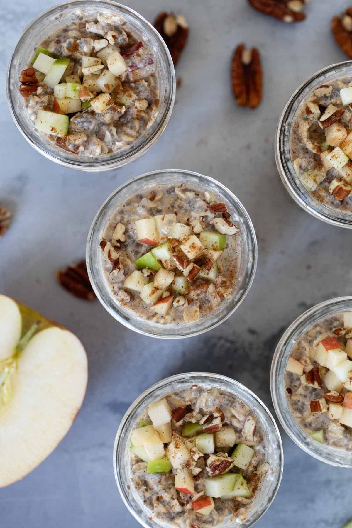 Apple Pie Overnight Oats in half pint jars, topped with chopped apples.