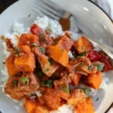 Plate with a serving of bbq chicken and vegetables, with sweet potatoes and bell peppers.