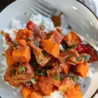 Plate with a serving of bbq chicken and vegetables, with sweet potatoes and bell peppers.