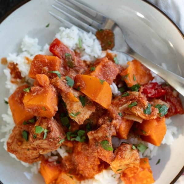 Plate with a serving of bbq chicken and vegetables, with sweet potatoes and bell peppers.