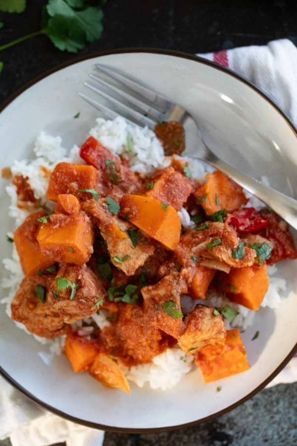 Plate with a serving of bbq chicken and vegetables, with sweet potatoes and bell peppers.