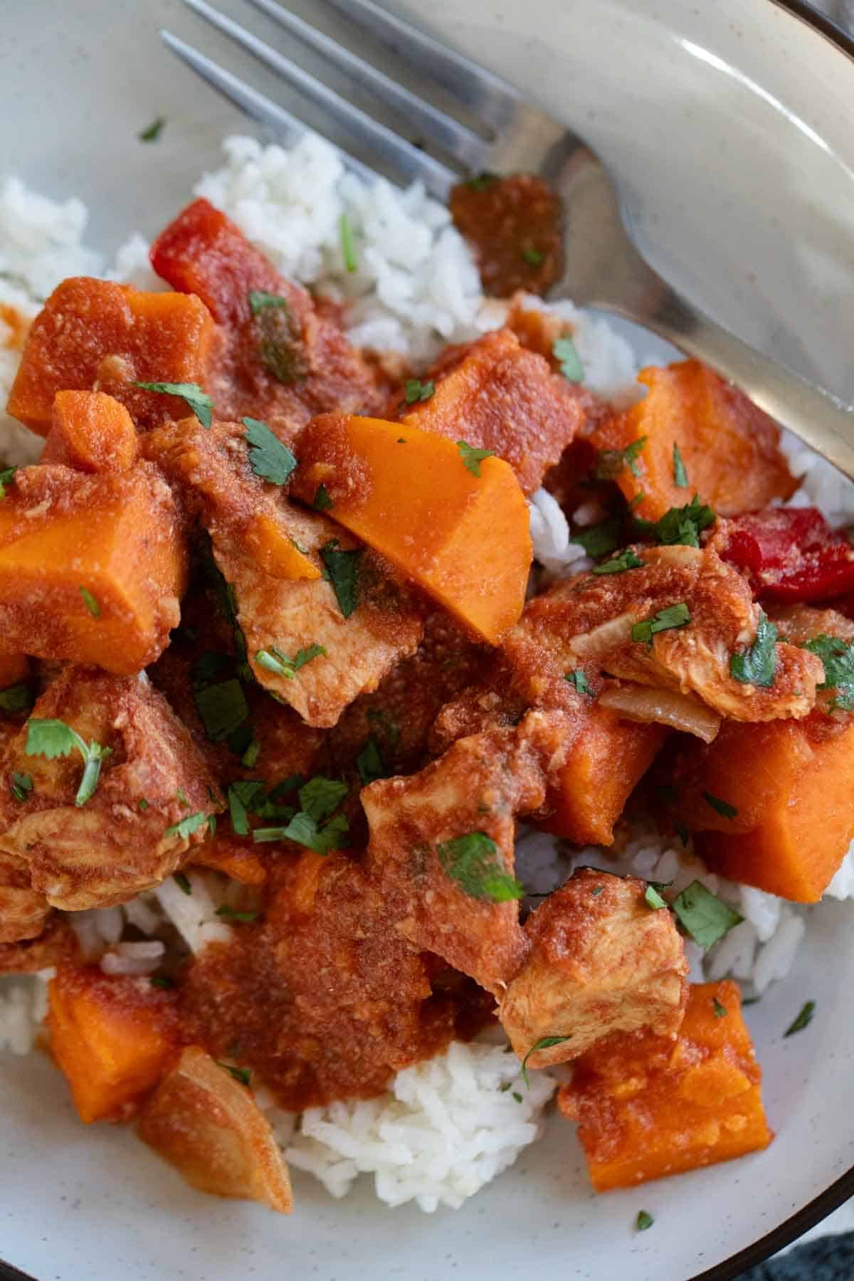 Slow cooker bbq chicken and vegetables served over rice and topped with cilantro.