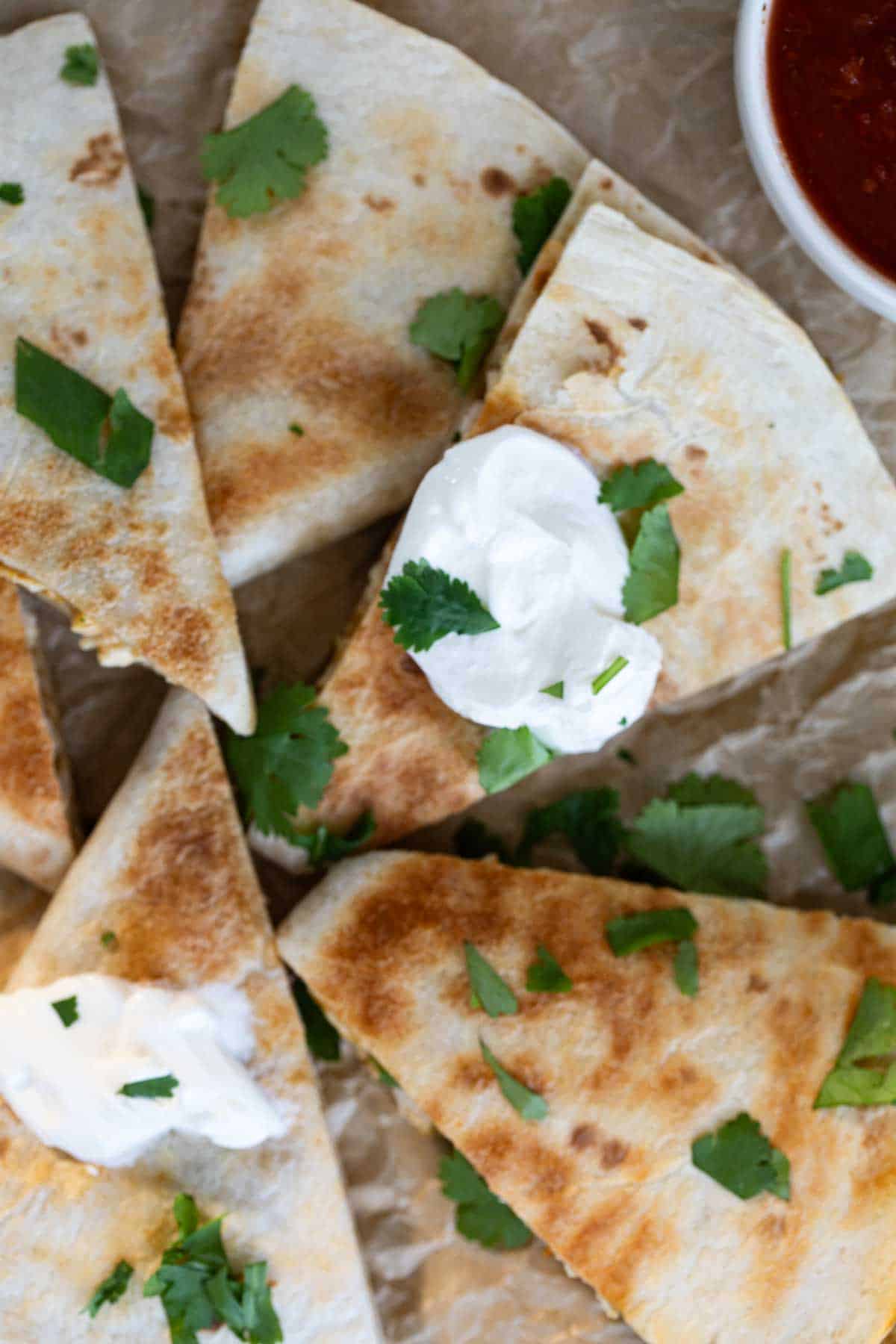 Creamy Chicken Quesadillas topped with sour cream and cilantro.