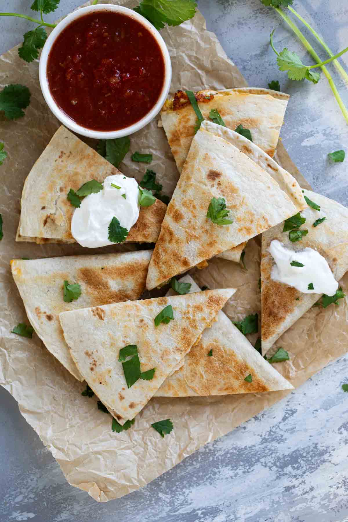 Creamy Chicken Quesadillas cut into triangles, served with salsa and cilantro.