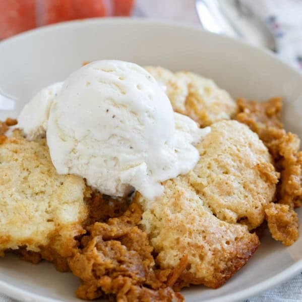 Serving of Pumpkin Cobbler in a bowl topped with vanilla ice cream.
